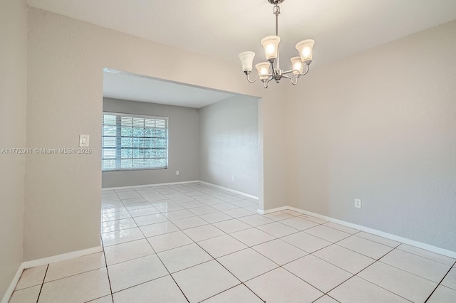 unfurnished room with light tile patterned floors, a notable chandelier, and baseboards