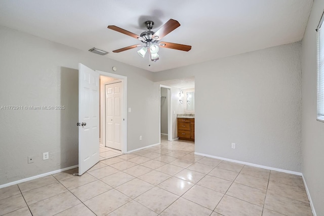 unfurnished bedroom featuring baseboards, light tile patterned floors, a ceiling fan, connected bathroom, and visible vents