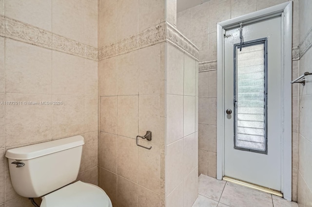 bathroom featuring toilet, tile patterned floors, and tile walls
