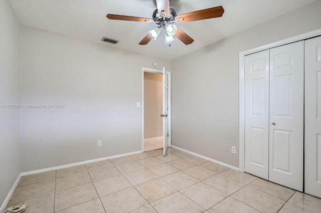 unfurnished bedroom with a closet, light tile patterned floors, baseboards, and visible vents
