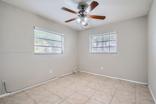 unfurnished room featuring ceiling fan, a textured wall, and baseboards