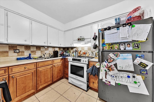 kitchen with decorative backsplash, white electric stove, a sink, light tile patterned floors, and freestanding refrigerator