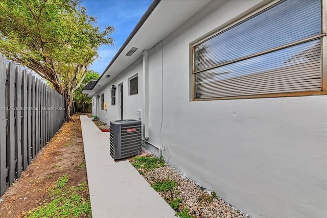 view of home's exterior with stucco siding, fence, and central AC unit