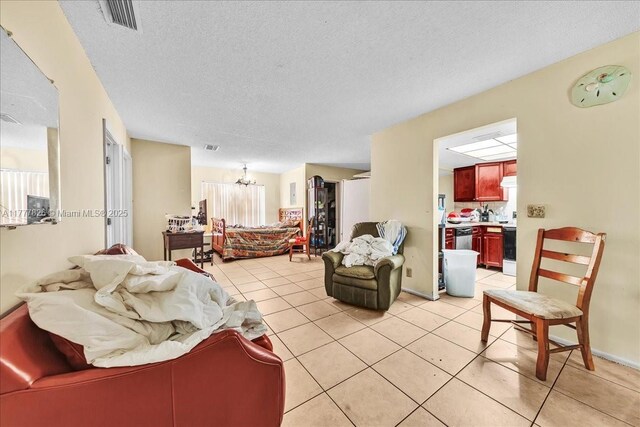 living room with light tile patterned flooring, a notable chandelier, visible vents, and a textured ceiling