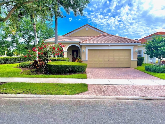 mediterranean / spanish home featuring a tile roof, decorative driveway, a garage, and stucco siding