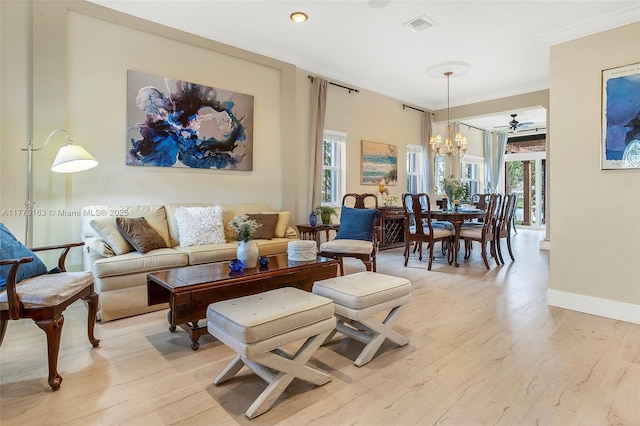 living area featuring crown molding, light wood-style flooring, and plenty of natural light