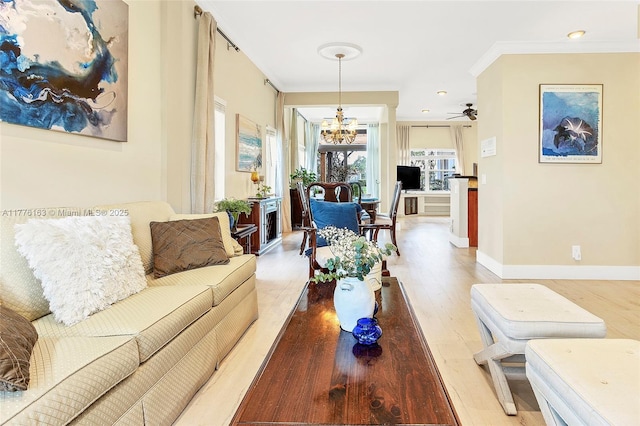 living area featuring light wood-style flooring, baseboards, and crown molding