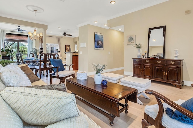 living room featuring baseboards, light wood-type flooring, crown molding, recessed lighting, and ceiling fan with notable chandelier