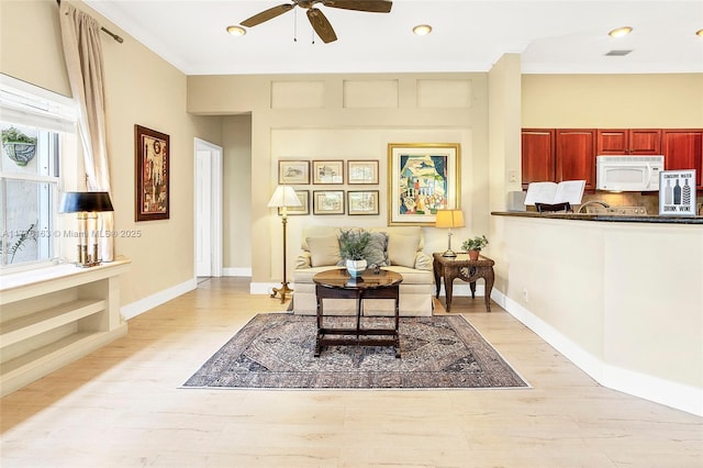 sitting room with light wood-style flooring, crown molding, ceiling fan, and visible vents
