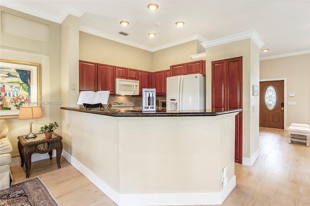 kitchen with white appliances, a peninsula, light wood-type flooring, visible vents, and reddish brown cabinets