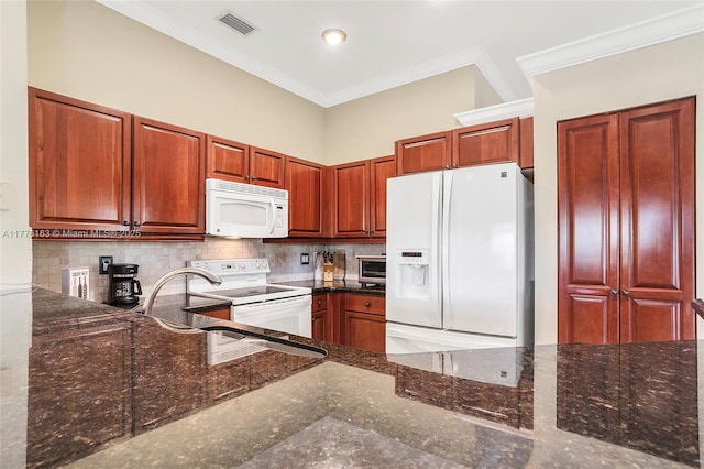 kitchen with visible vents, white appliances, crown molding, dark stone counters, and backsplash