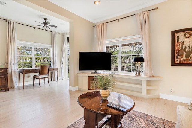 living area featuring visible vents, baseboards, a ceiling fan, and wood finished floors