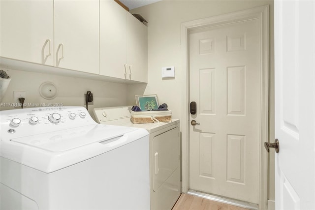 washroom with washing machine and dryer, light wood-type flooring, and cabinet space