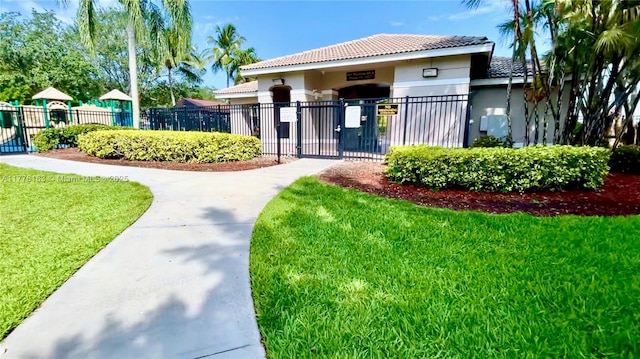 view of front of home featuring a front yard, a fenced front yard, a tiled roof, stucco siding, and a gate