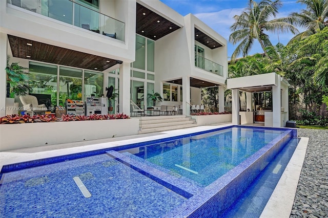 view of swimming pool featuring an infinity pool, a patio area, and exterior kitchen