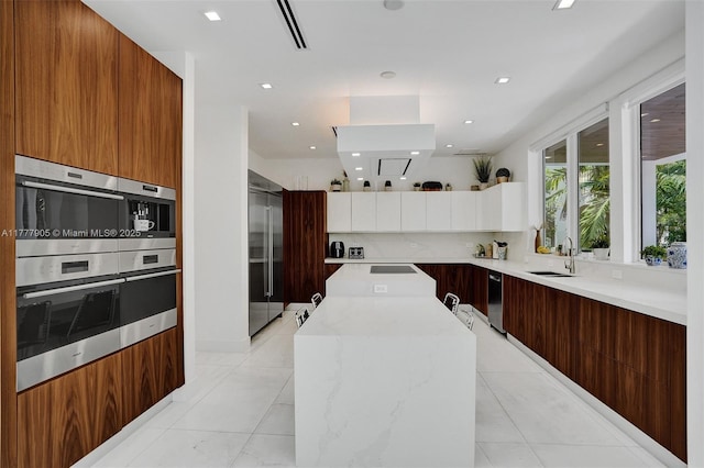 kitchen with a sink, a center island, modern cabinets, and appliances with stainless steel finishes