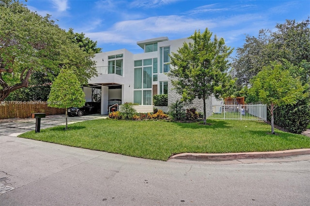 contemporary home featuring stucco siding, fence, a balcony, and a front yard