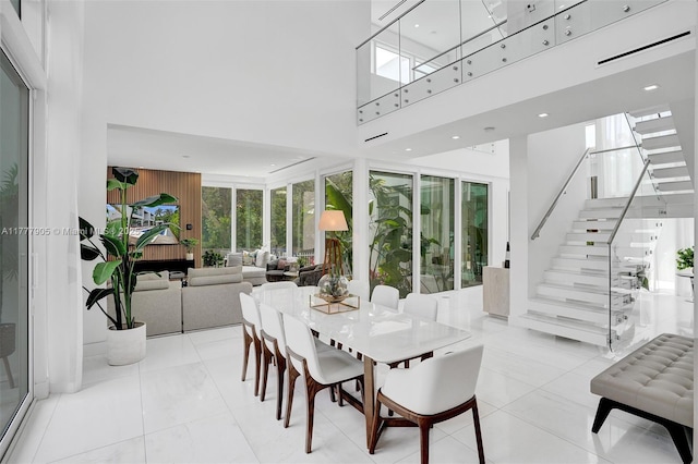 dining room featuring stairs, recessed lighting, and a towering ceiling