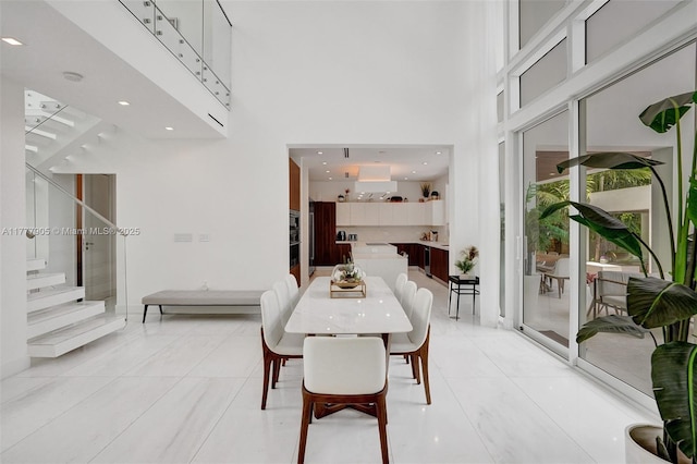 dining area with stairs, recessed lighting, and a towering ceiling
