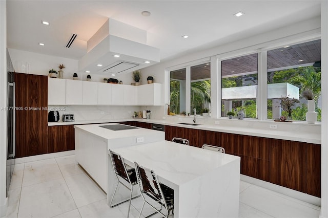 kitchen with a center island, modern cabinets, white cabinets, and tasteful backsplash