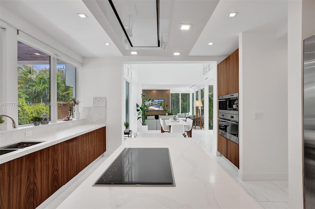 kitchen with a sink, modern cabinets, black electric stovetop, and brown cabinets