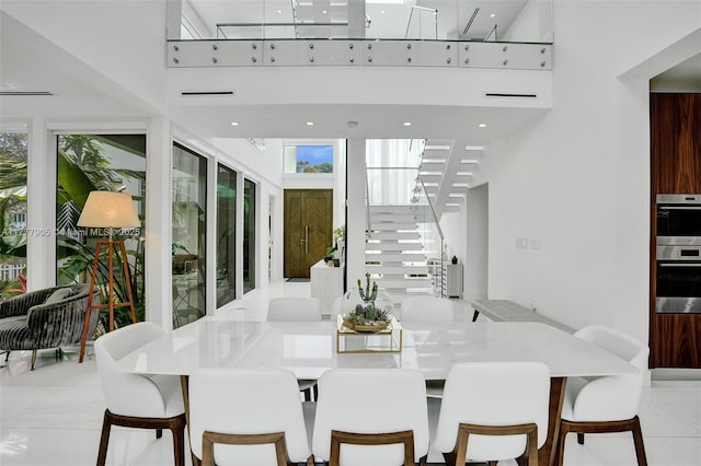 dining room featuring tile patterned flooring, stairs, and a towering ceiling