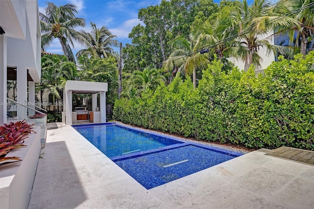 outdoor pool with an outdoor kitchen and a patio