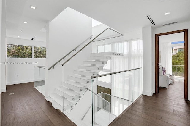 stairway with wood-type flooring, attic access, baseboards, and visible vents