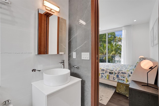 ensuite bathroom featuring vanity, ensuite bath, wood finished floors, and tile walls