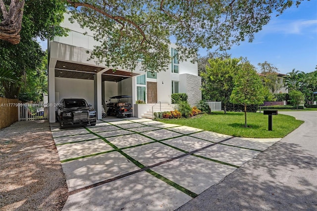 exterior space featuring fence, stucco siding, a lawn, a carport, and driveway