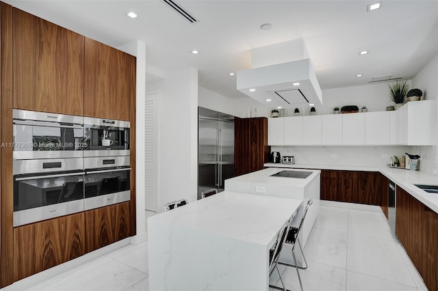 kitchen featuring modern cabinets, a kitchen breakfast bar, a center island, recessed lighting, and black electric cooktop