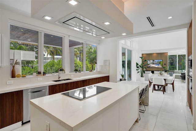 interior space featuring stainless steel dishwasher, modern cabinets, light countertops, black electric cooktop, and a sink