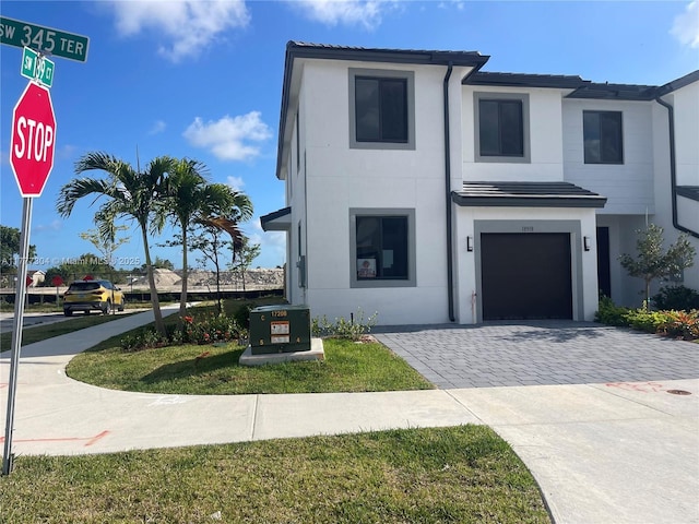 view of front of property with driveway, an attached garage, a tile roof, and stucco siding