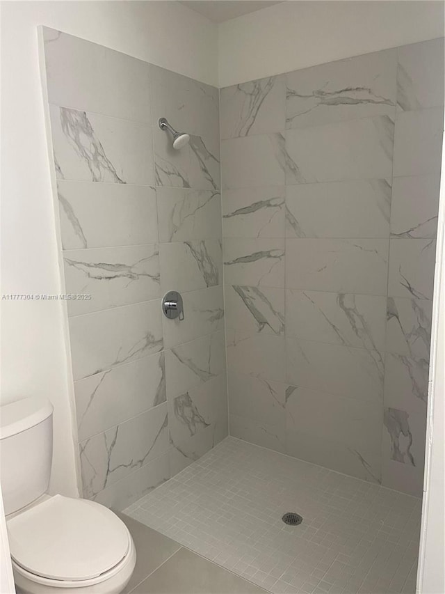 full bathroom featuring toilet and tiled shower