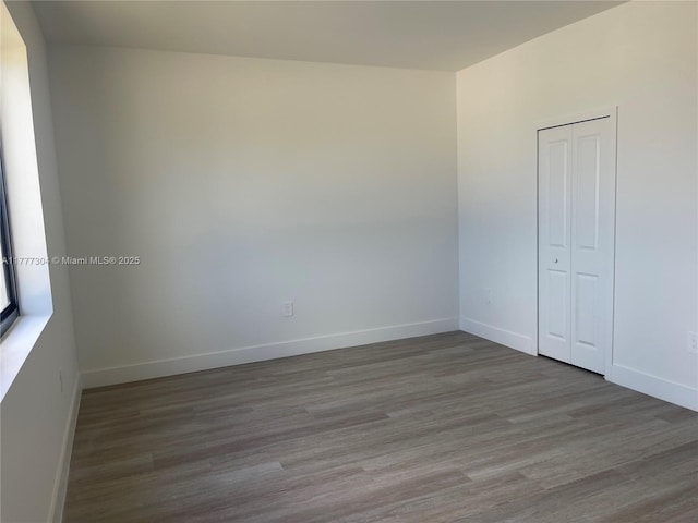 unfurnished room with baseboards and wood finished floors