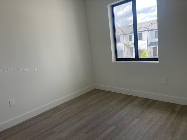 empty room featuring baseboards and dark wood-style floors