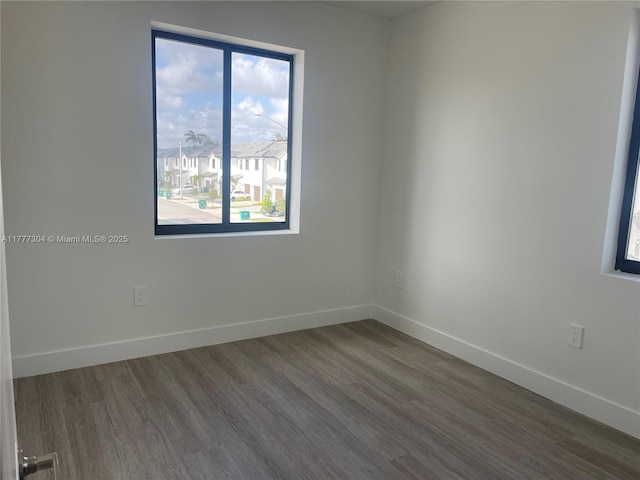 unfurnished room with baseboards, wood finished floors, and a residential view