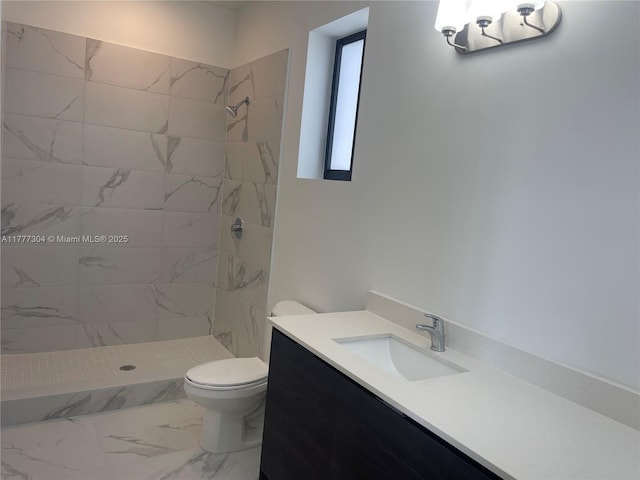 bathroom featuring marble finish floor, vanity, toilet, and tiled shower