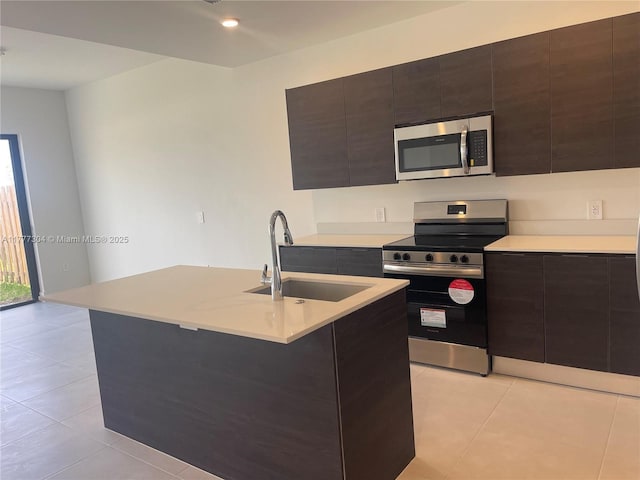 kitchen featuring light countertops, modern cabinets, appliances with stainless steel finishes, a sink, and light tile patterned floors