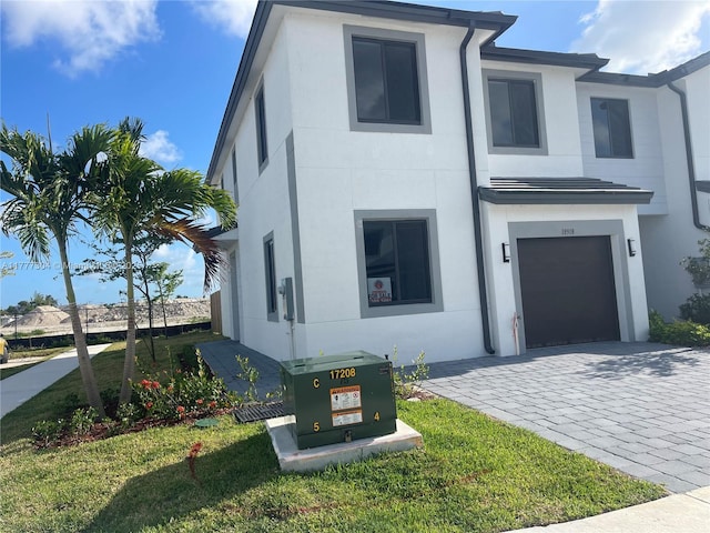 modern home featuring decorative driveway, stucco siding, and an attached garage