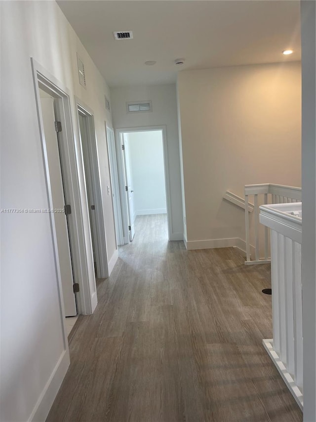 hallway featuring baseboards, an upstairs landing, visible vents, and wood finished floors