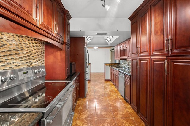 4340 NW 6th St, Plantation, FL 33317 - kitchen with dark stone countertops, decorative backsplash, a sink, reddish brown cabinets, and appliances with stainless steel finishes
