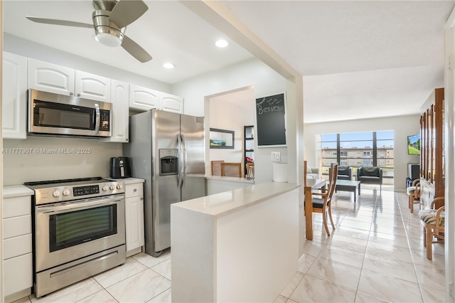 kitchen featuring light countertops, a ceiling fan, appliances with stainless steel finishes, a peninsula, and white cabinets