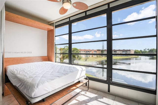 tiled bedroom featuring a water view and expansive windows