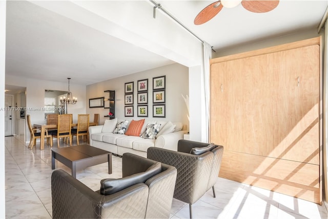 living area with marble finish floor and ceiling fan with notable chandelier