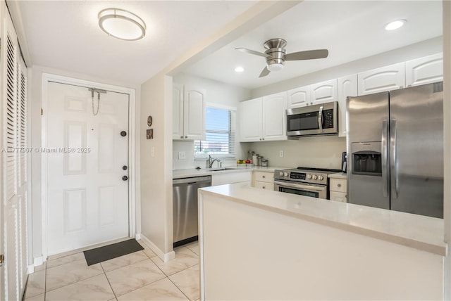 kitchen with white cabinets, light countertops, ceiling fan, stainless steel appliances, and a sink