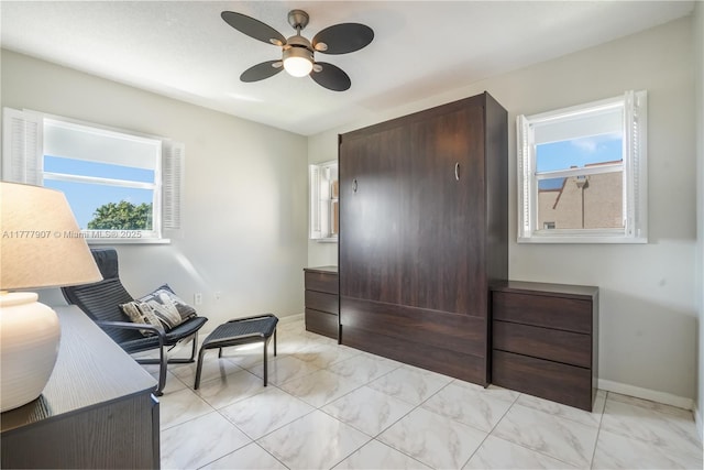 sitting room featuring a ceiling fan and baseboards