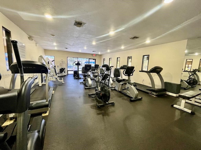 gym featuring baseboards, a textured ceiling, and visible vents