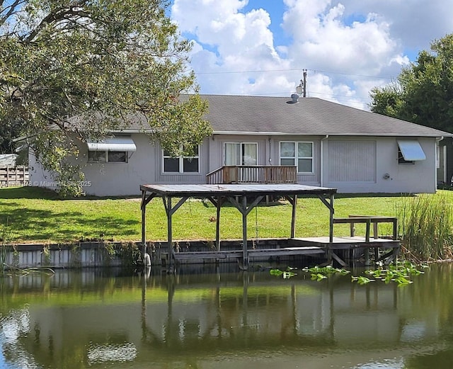 rear view of property with a lawn, a shingled roof, and a water view