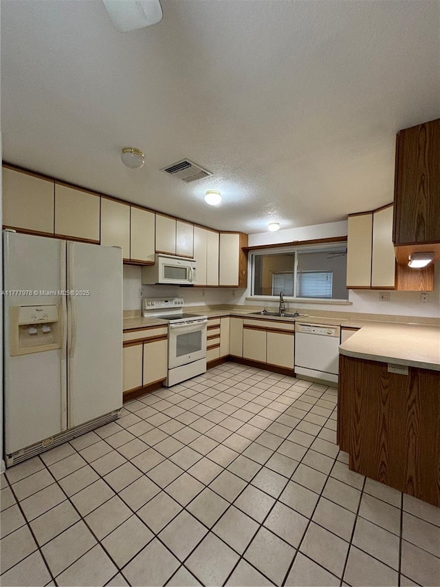 kitchen featuring a sink, light tile patterned flooring, visible vents, white appliances, and light countertops